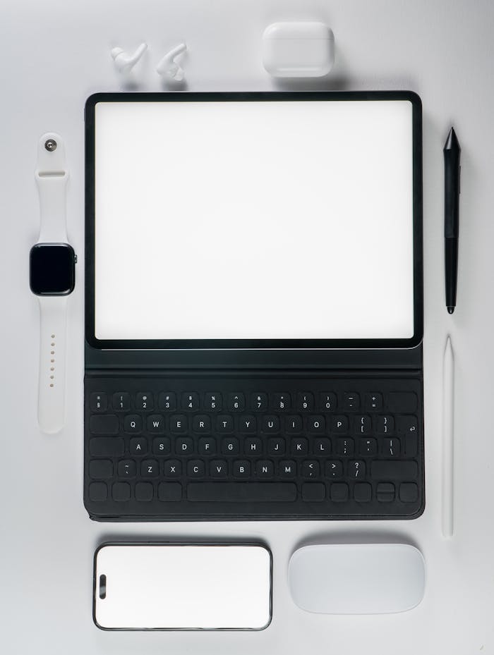 A flat lay of modern tech gadgets featuring a tablet, smartphone, and accessories on a white background.